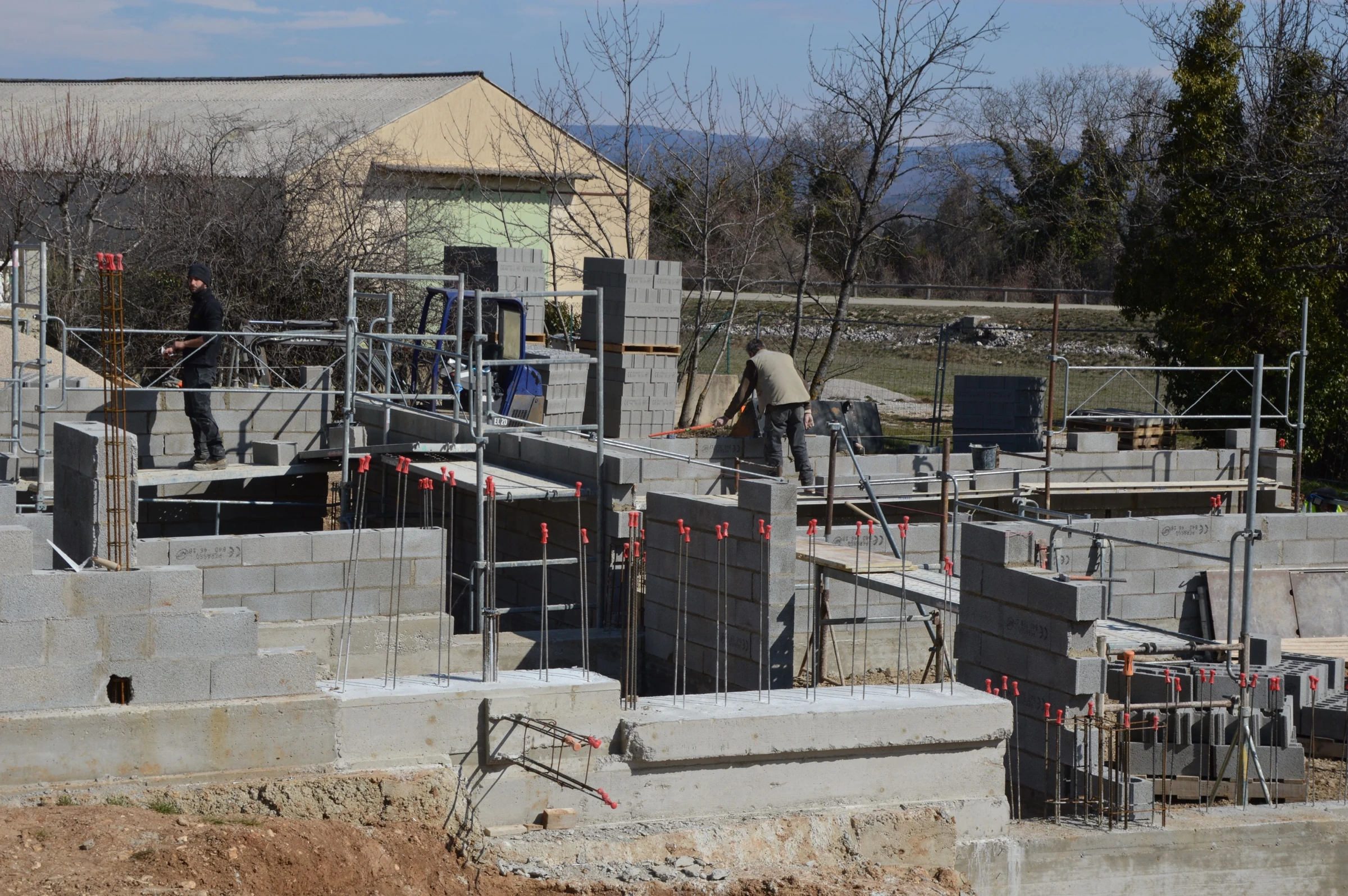 Chantier de maçonnerie en cours, deux compagnons sur les murs en parpaings